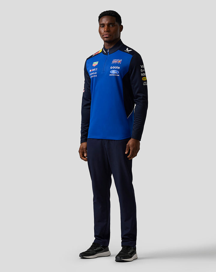 Male model wearing navy and blue Oracle Red Bull Racing Teamline quarter zip midlayer boasting sponsor logos on chest and sleeves