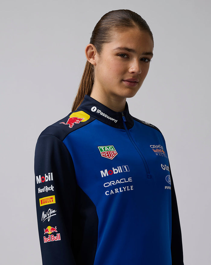 Female model wearing Oracle Red Bull Racing Teamline Quarter Zip Midlayer in Night Sky blue with navy sleeves and branding on the chest