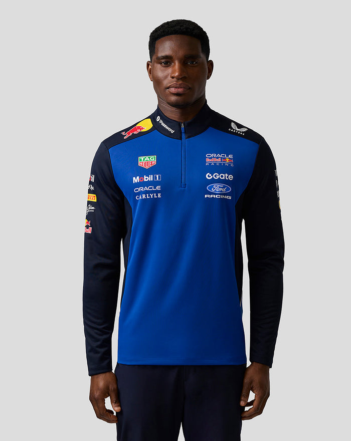Male model in Oracle Red Bull Racing Teamline Quarter Zip Midlayer in Night Sky blue with navy sleeves and sponsor logos on the chest and sleeve