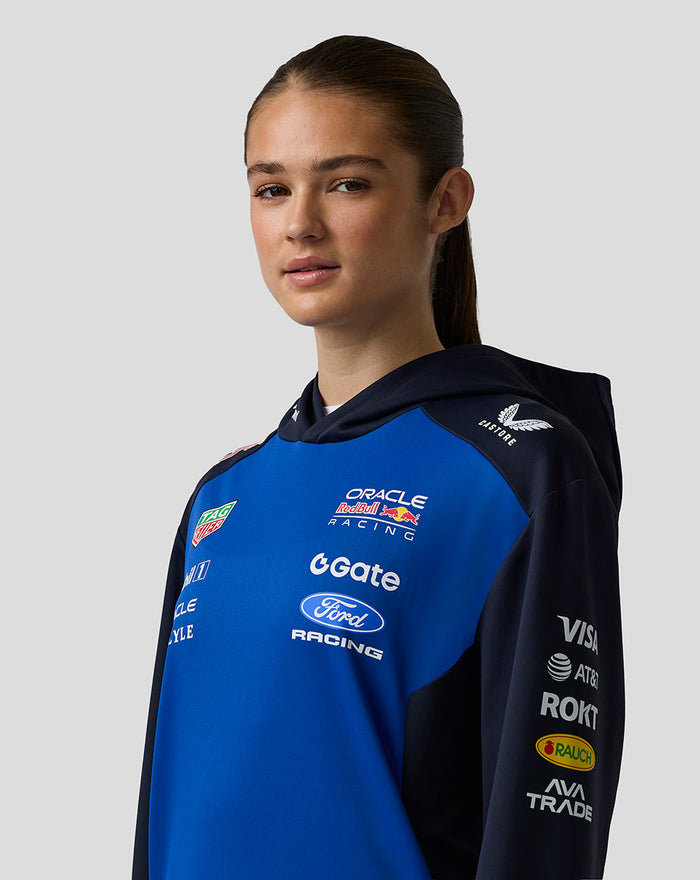 Female model wearing Oracle Red Bull Racing Teamline Overhead Hoodie in night sky blue with navy sleeves and race logos.
