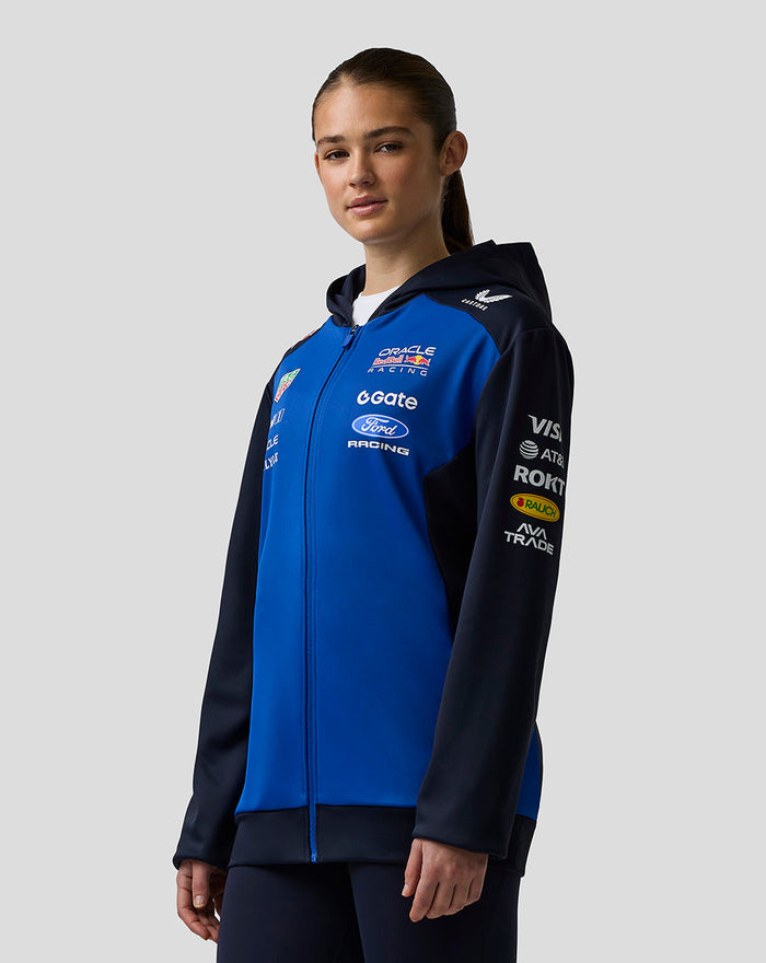 Female model wearing blue and navy Oracle Red Bull Racing Teamline jacket with racing logos on chest and sleeve