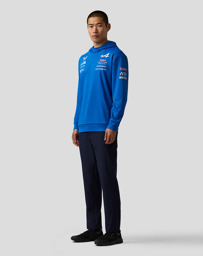 Side profile of a male model wearing a blue BWT Alpine Formula One Team hoodie with chest and sleeve logos.