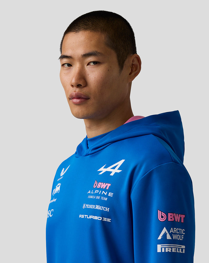Close-up of a man wearing a blue BWT Alpine Formula One Team pullover hoodie with chest and sleeve logos.