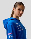Side profile of a woman wearing a blue BWT Alpine hoodie with chest sponsor logos and a lined hood.