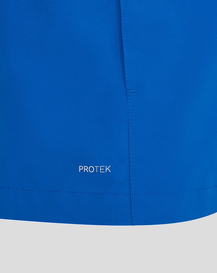Close up of blue rain jacket fabric showing PROTEK branding and a seam detail.