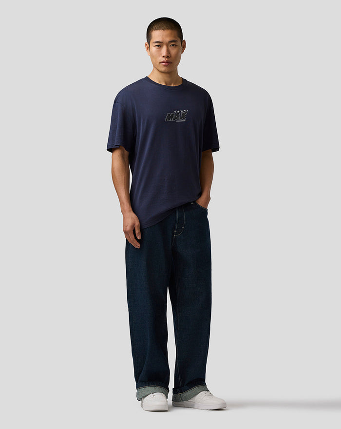 Male model wearing navy night sky Max Verstappen logo T shirt with relaxed fit denim jeans and white sneakers