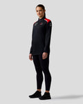 Female model wearing Official Haas Team Quarter Zip Midlayer in black with red shoulder panels and sponsor logos on the chest