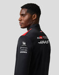 Back view of a model wearing a black Haas Team Quarter Zip Midlayer with back logos and sleeve branding for Singha Mphasis Commscope Zoomex