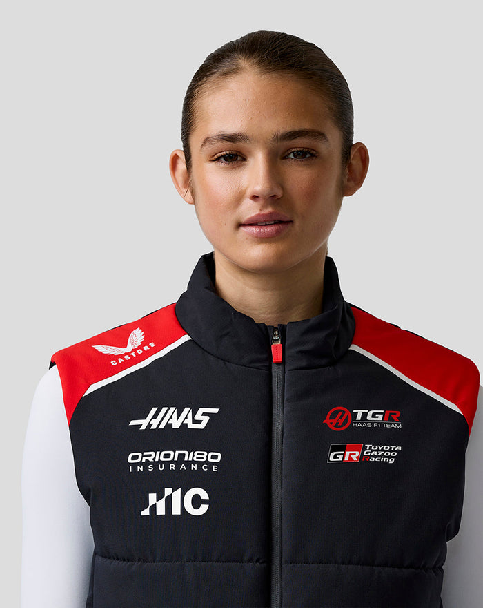 Front view of a female model wearing Official Haas Team Unisex Gilet with red shoulders and race team logos