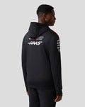 Rear view of a model wearing a black Official Haas Team pullover hoodie with a large white Haas logo on the back.