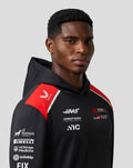 Male model wearing the Haas Team Pullover Hoodie in black with red shoulder panels, close-up profile view
