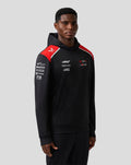 Front view of a male model wearing a black Haas Team pullover hoodie with red shoulder panels and white branding