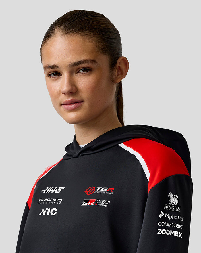 Female model in Haas Team pullover hoodie with black fabric red shoulder panels and team logos on chest