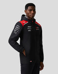 Male model wearing Haas Team water resistant jacket in black with red shoulder panels hood and front zip branding