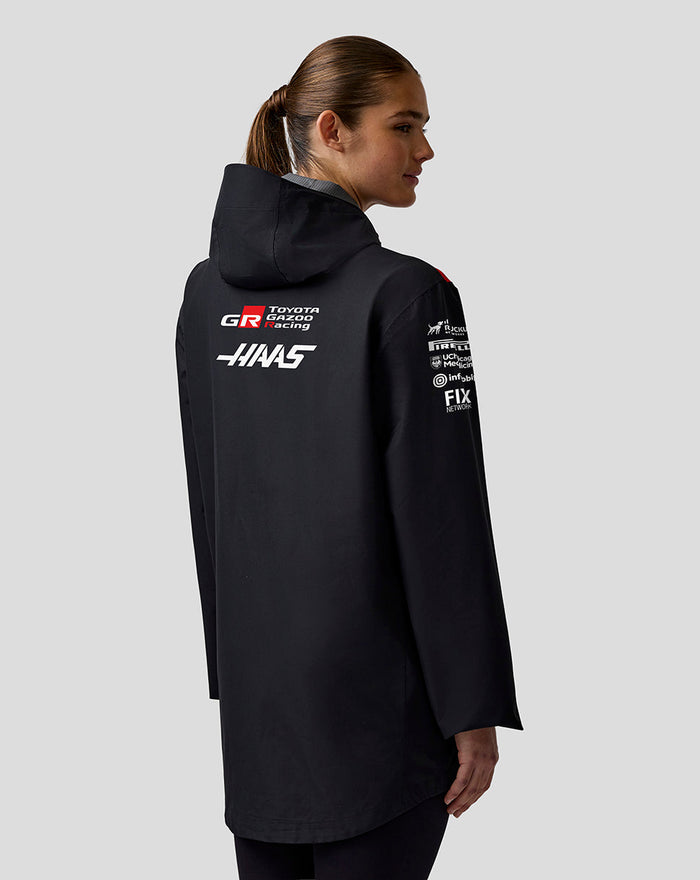 Rear view of black hooded Haas Team water-resistant jacket with red shoulder panels.