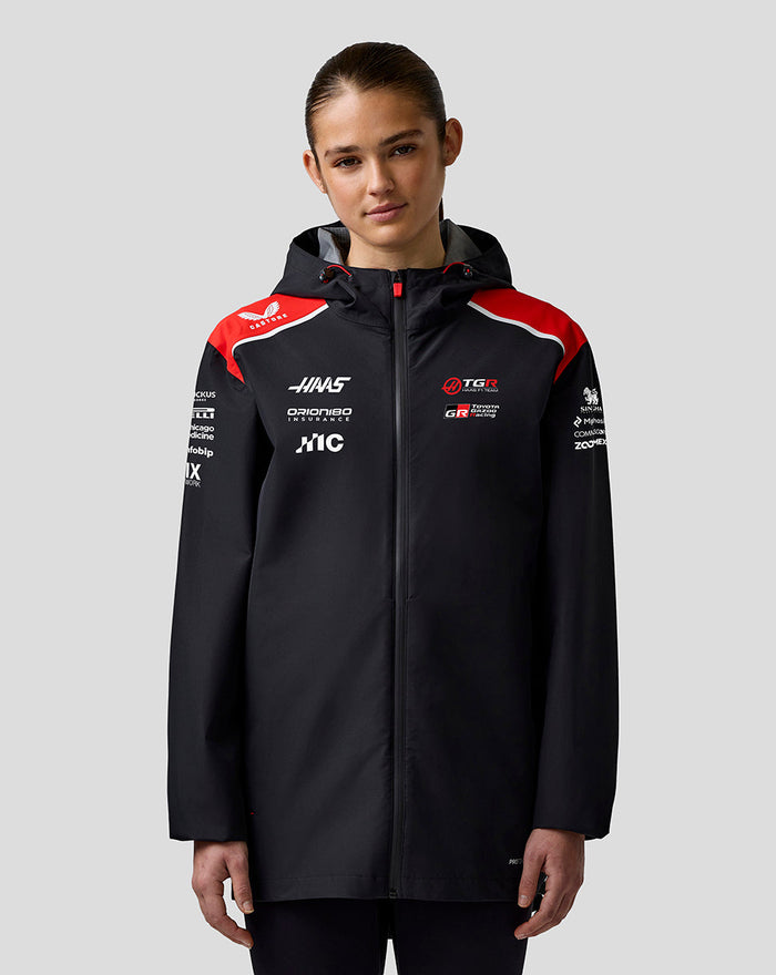 Female model wearing Haas Team Water Resistant Jacket with hood and branded chest logos.