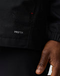 Haas Team water resistant jacket close up showing PROTEK logo on black fabric with red stitch detail