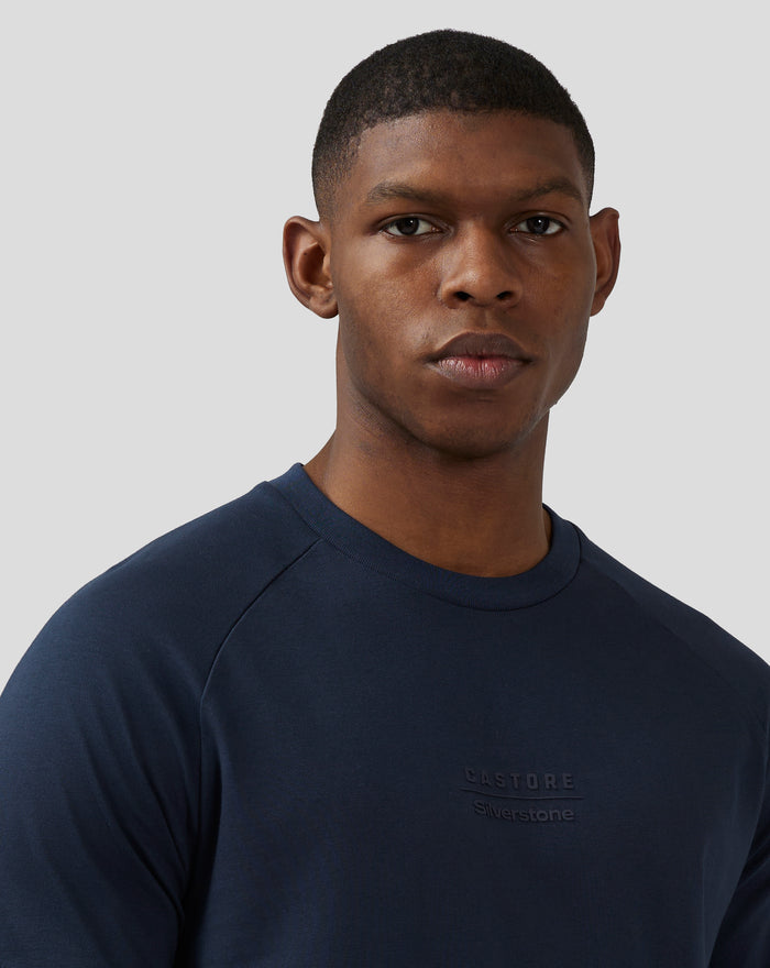 Close up of a navy unisex short sleeve tee on a man with embossed logos on the chest area