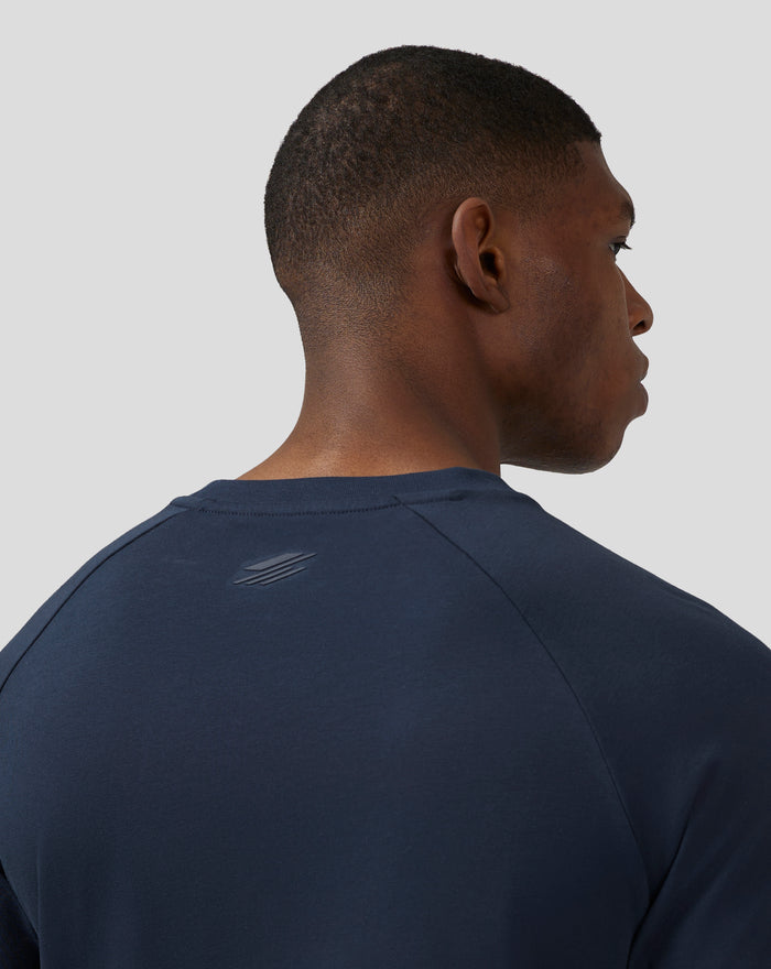 Back view of a woman wearing a navy unisex short sleeve tee with a back neck logo visible
