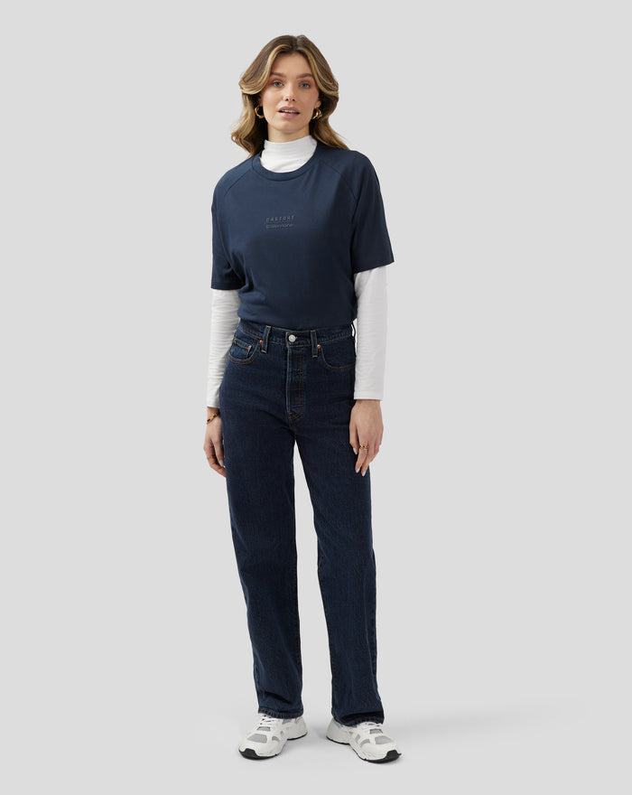 Female model wearing dark navy unisex Silverstone x Castore short sleeve T shirt with raglan sleeves and chest logo