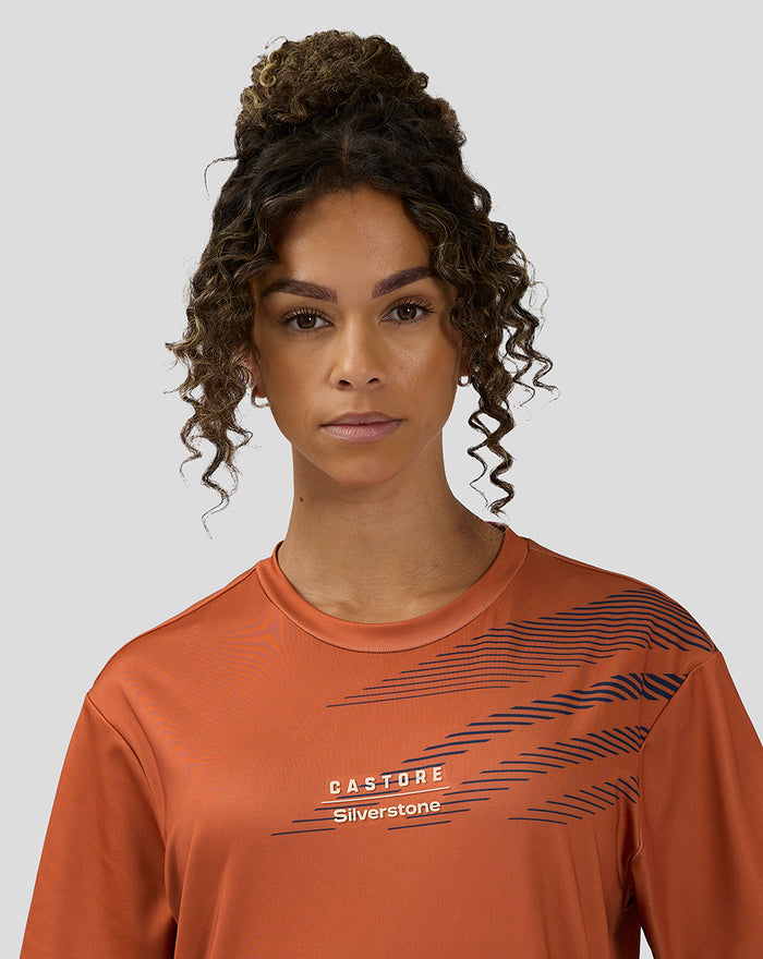 Close up of a woman wearing an orange rust unisex Silverstone sublimated short sleeve T shirt with diagonal navy print