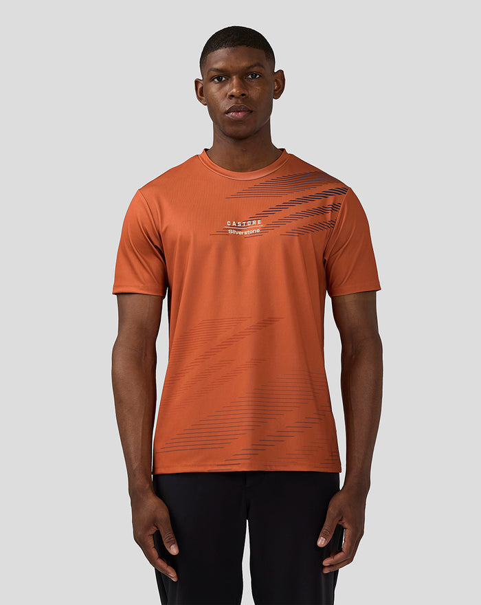 Front view of a model wearing an orange rust unisex Silverstone sublimated short sleeve T-shirt with a diagonal navy print.