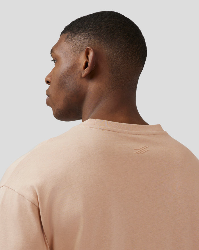 Profile view of a male model in a doeskin tee featuring embossed chest branding from the Silverstone Castore collection.