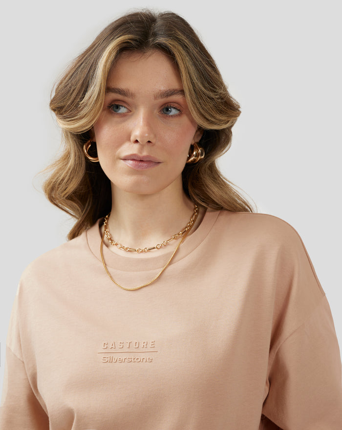 Close up of the beige doeskin tee showing embossed Castore Silverstone logo on the chest.