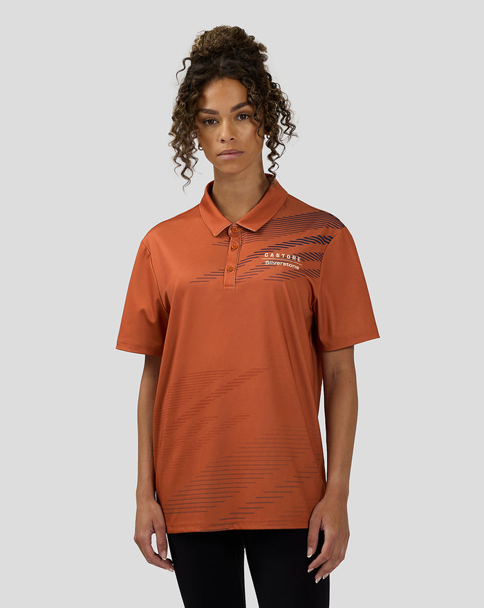 Front view of a woman wearing orange rust sublimated short sleeve polo with navy diagonal lines on the chest.