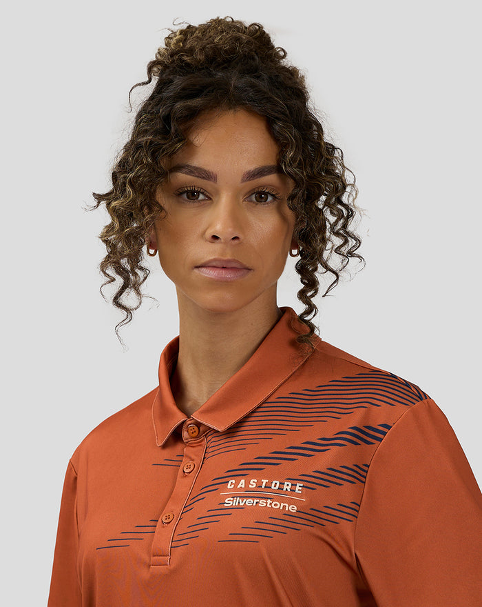 Close up of orange rust Castore Silverstone polo showing navy sublimated stripes and logo on chest