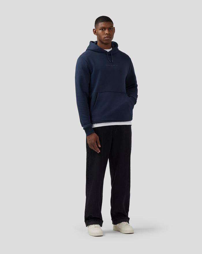 Front view of a model wearing a navy Silverstone Core Graphic Hoodie with a drawstring hood, center chest print and front kangaroo pocket.
