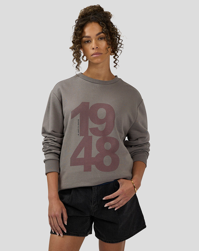 Woman modeling a charcoal Silverstone Core Sweatshirt with a bold mauve 1948 graphic