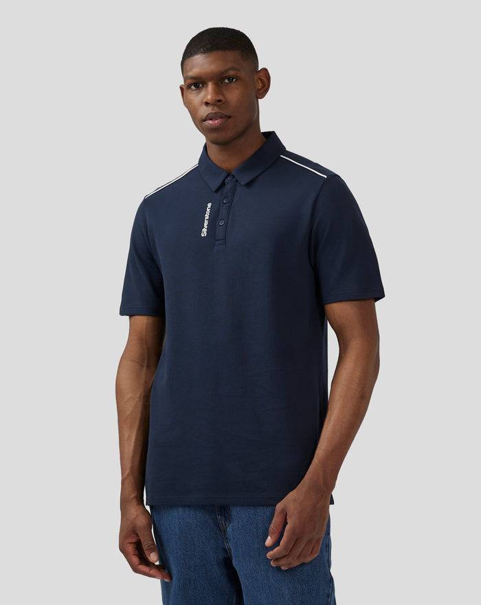 Man wearing navy Silverstone polo with white piping along shoulder seams and vertical Silverstone logo on front placket
