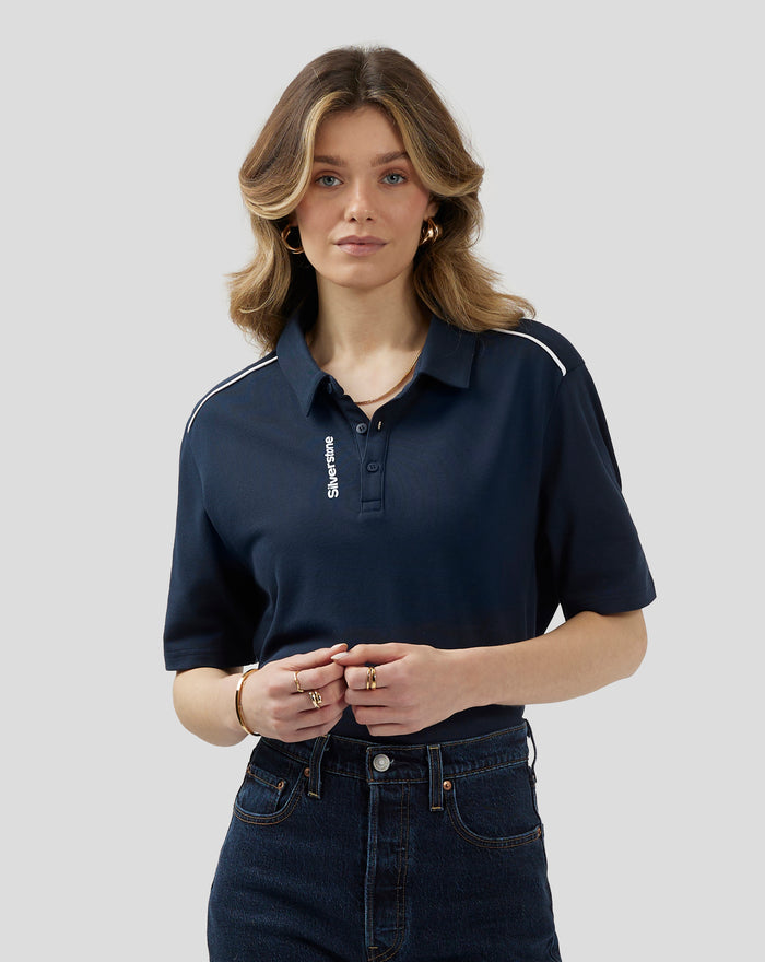 Model wearing navy polo shirt with white piping along shoulders and a three button placket.