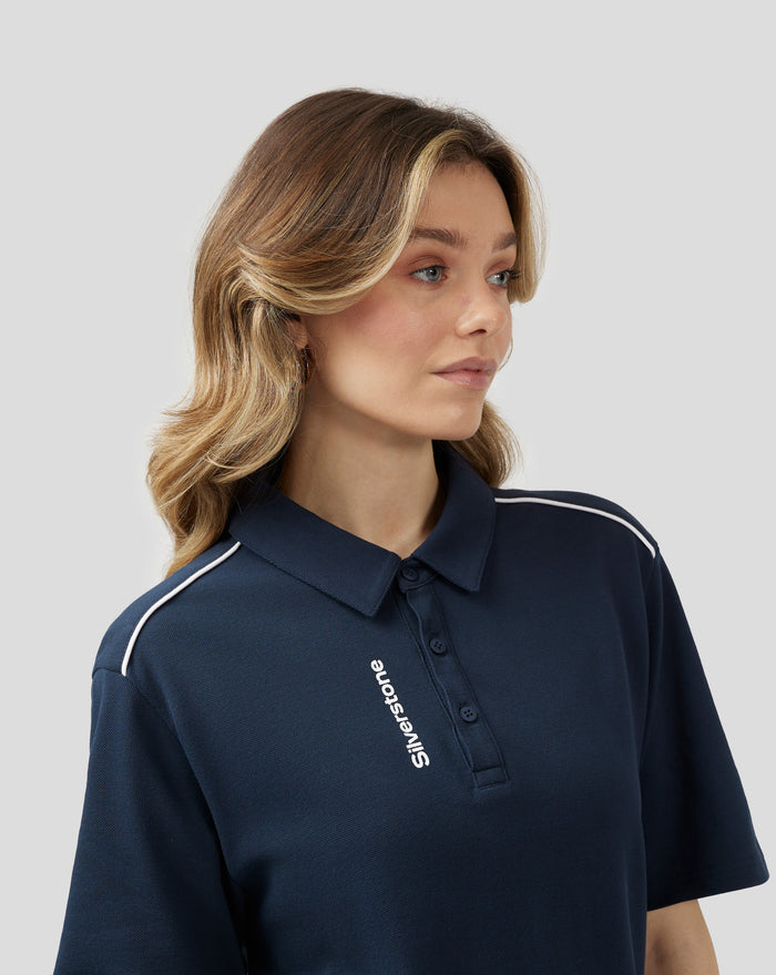 Close up of model wearing navy polo with white piping along shoulder seam and front button placket