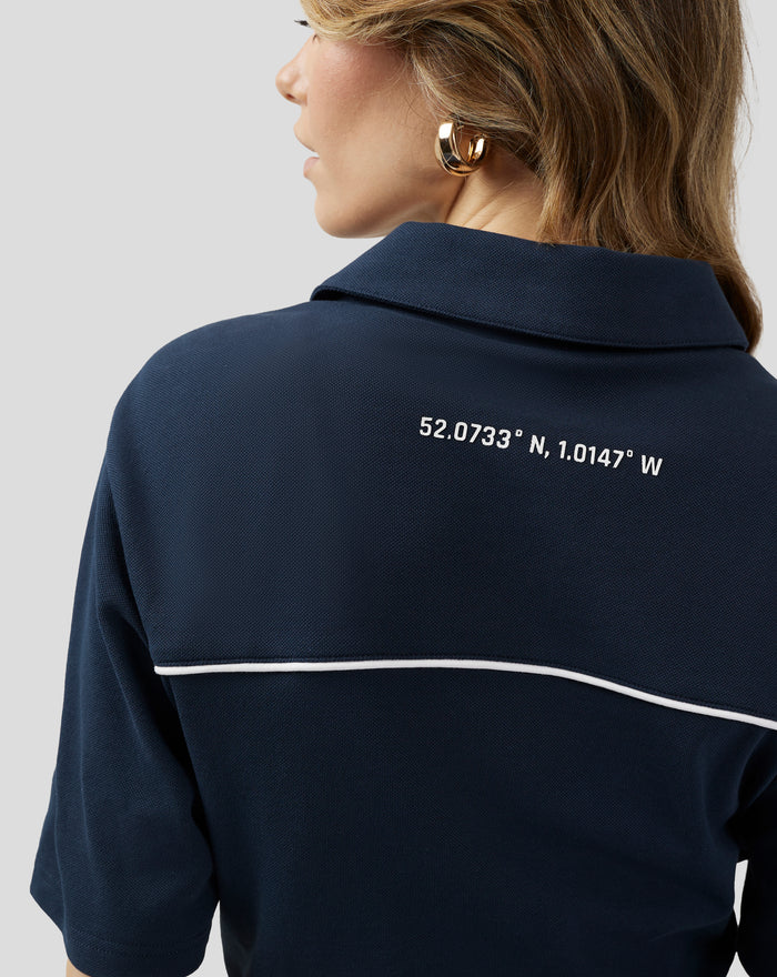 Back view of navy polo with white shoulder piping and coordinates printed across the back.