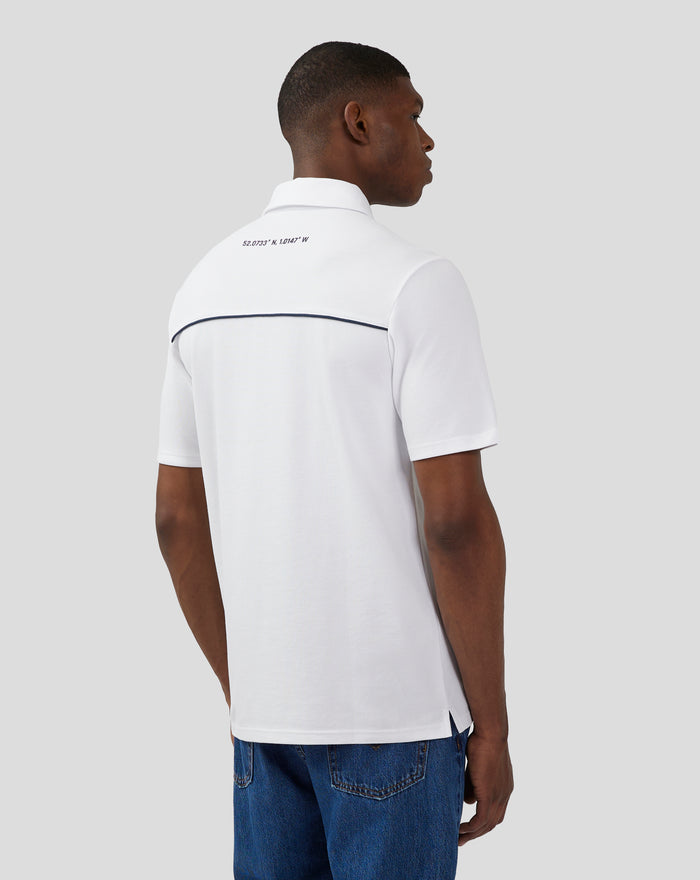 Back view of a white polo showing coordinates printed on the upper back and dark piping along the back yoke