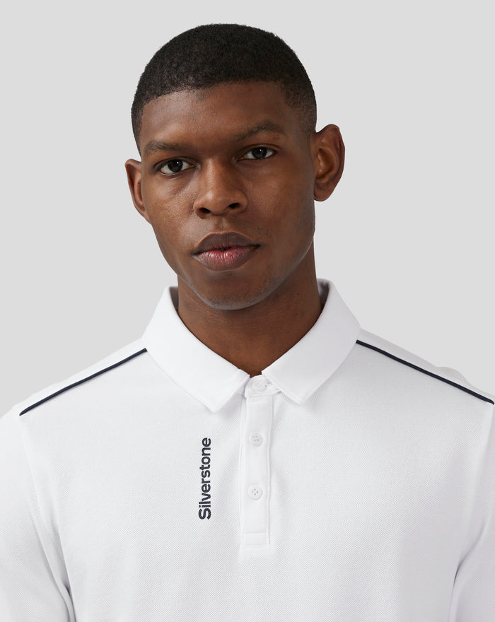 Male model wearing a white Silverstone Core Polo with navy piping on the shoulder seams and placket branding.