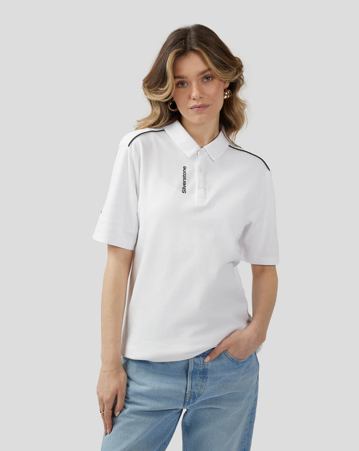 Front view of a model wearing a white Silverstone Core Polo with black piping along the shoulders and a vertical Silverstone logo on the placket