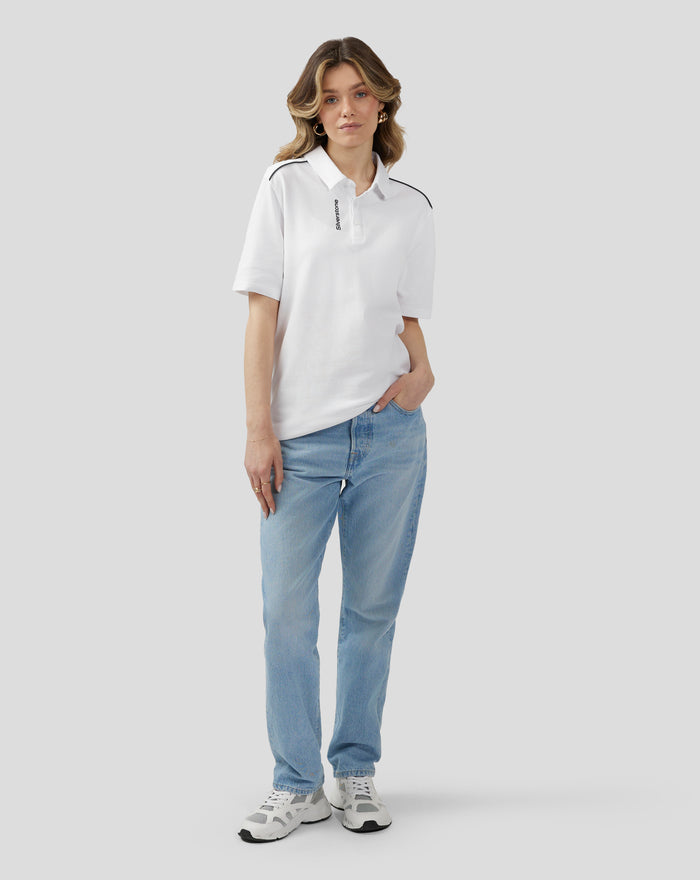 Model wearing white polo with black shoulder piping and vertical Silverstone branding along the placket.