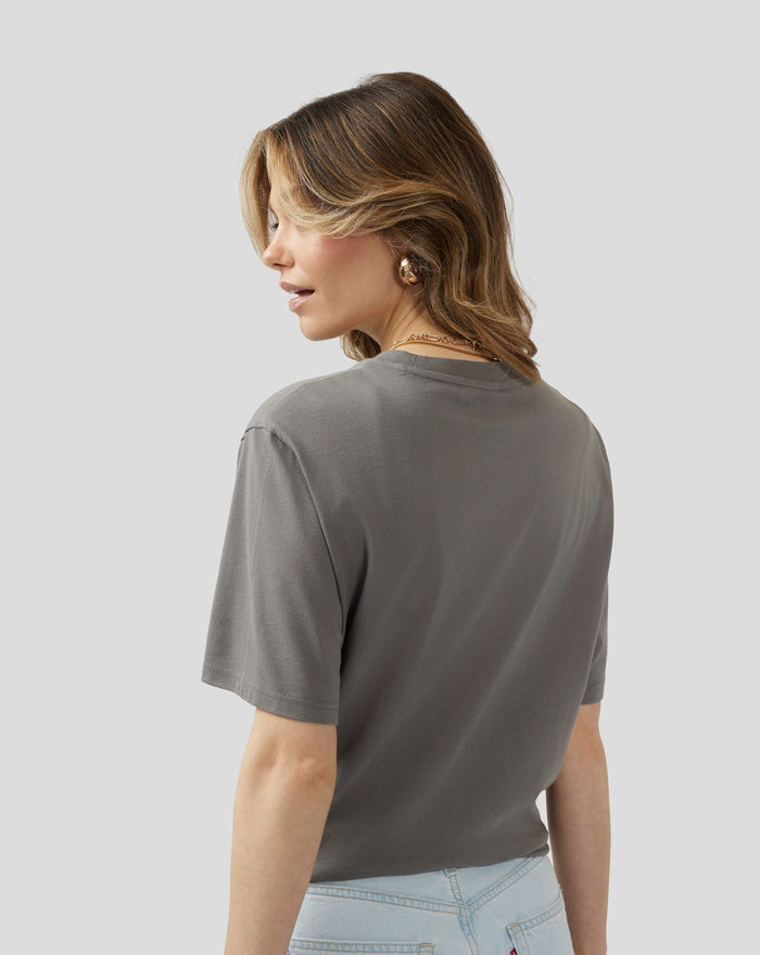 Three quarter back view of a model in the charcoal Silverstone Core 1948 T-Shirt