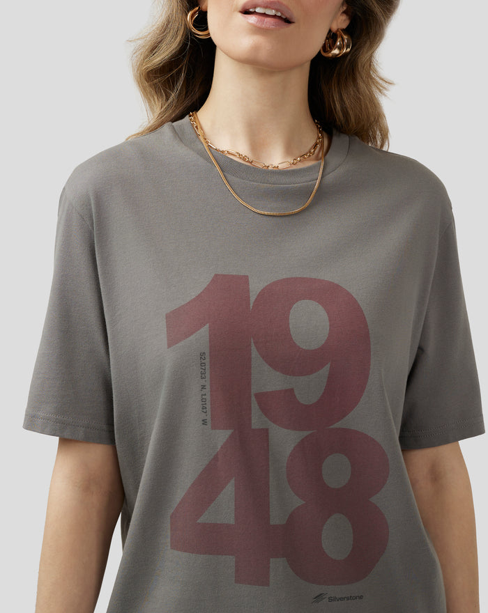 Close crop of a charcoal grey T shirt with a large pink graphic across the front and a small Silverstone logo at the hem.