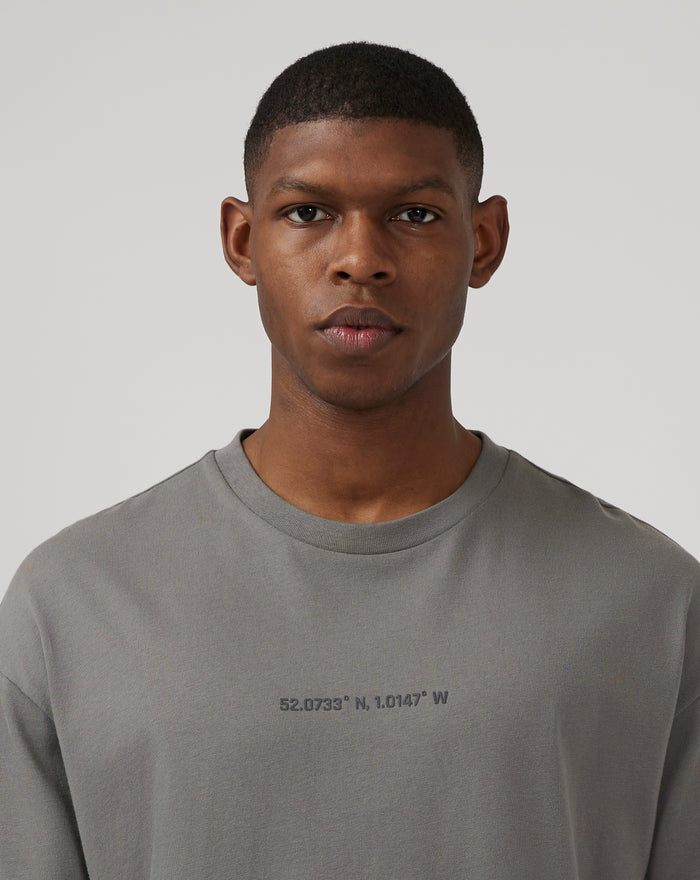 Close up of chest coordinates graphic on charcoal grey oversized T shirt