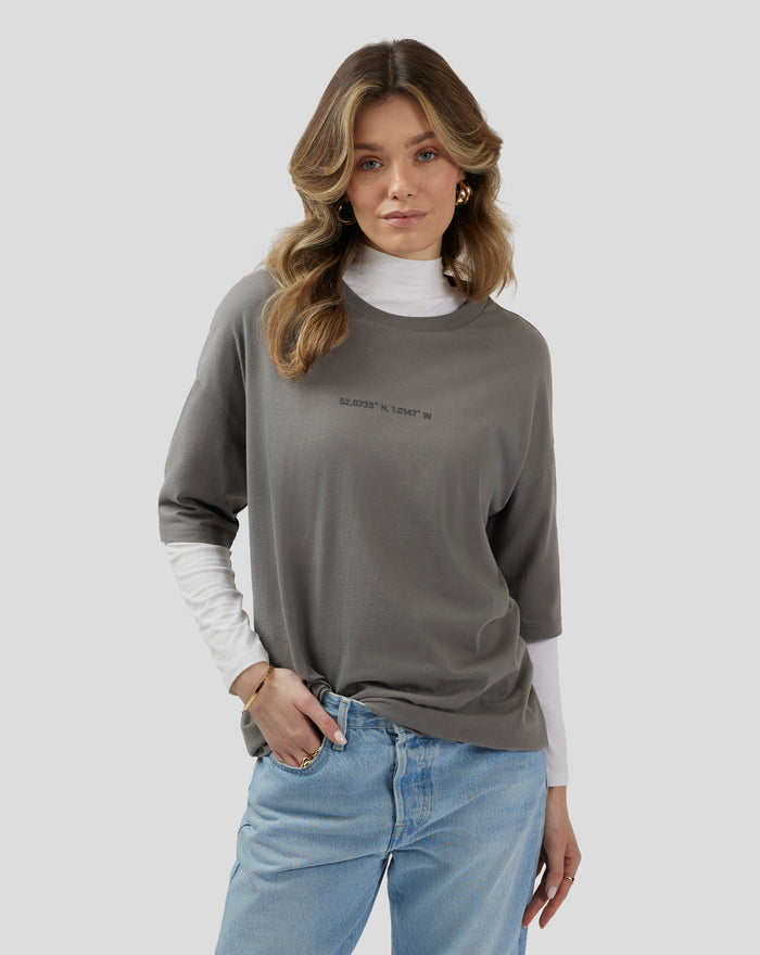 Back view of a model in a charcoal grey oversized T-shirt with a large Silverstone graphic on the back.