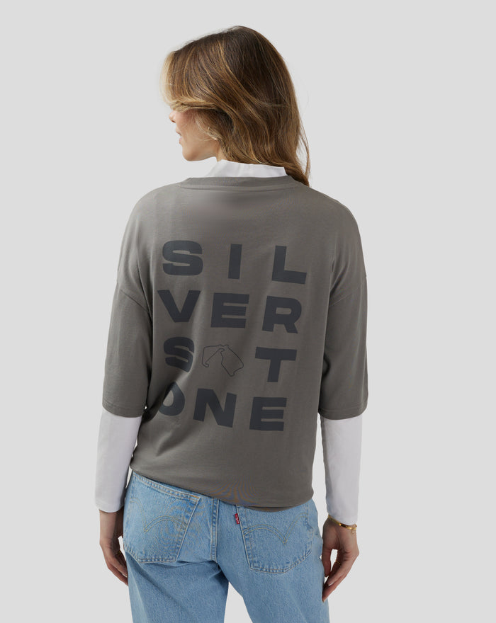 Back view of a woman wearing charcoal grey Silverstone Core Oversized T Shirt with bold back lettering and small graphic icons
