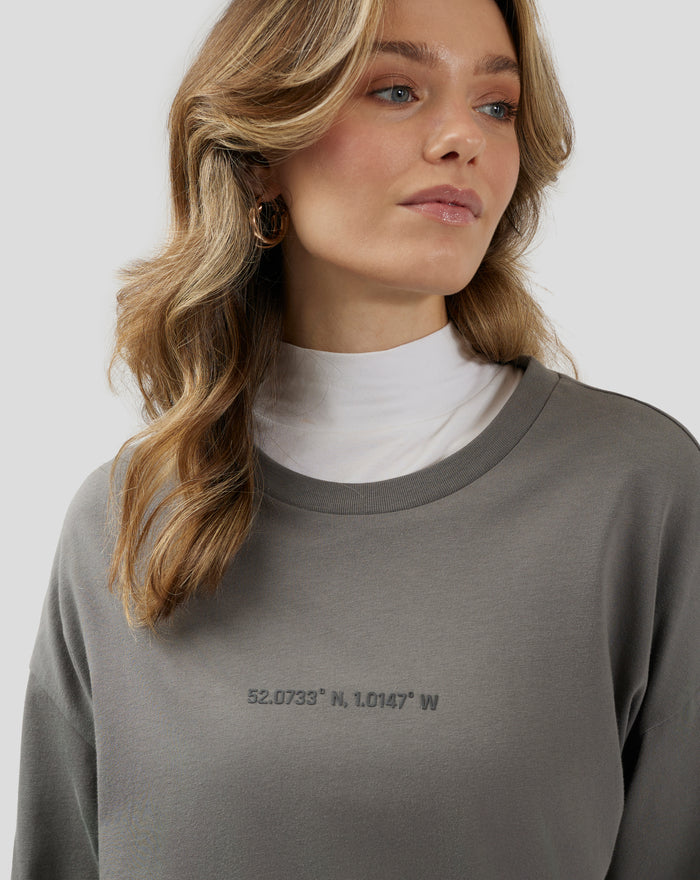 Back view of a woman wearing charcoal grey Silverstone Core Oversized T Shirt with a large back graphic